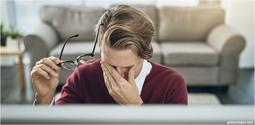 un hombre se frota los ojos frente a una computadora