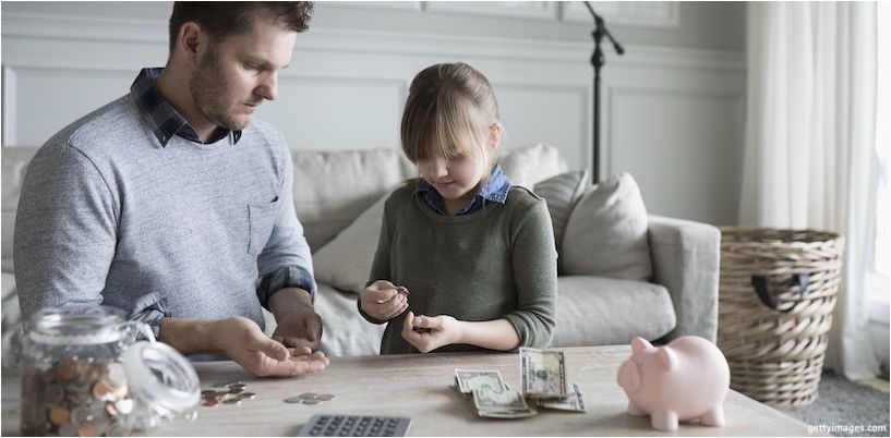 papá e hija ponen dinero en una alcancía