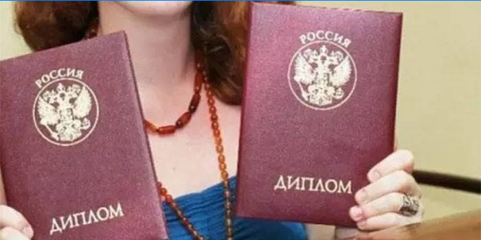 Una niña con dos diplomas en sus manos.