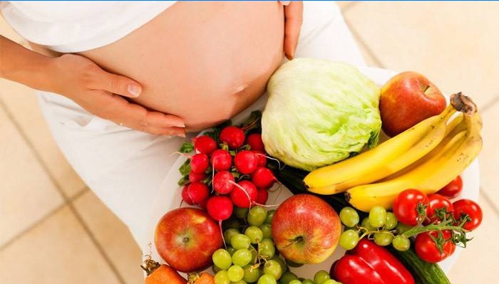 Mujer embarazada con frutas y verduras.