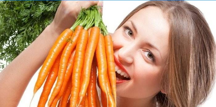Niña sostiene un montón de zanahorias