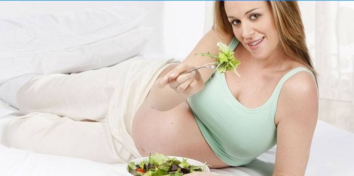 Niña embarazada come ensalada