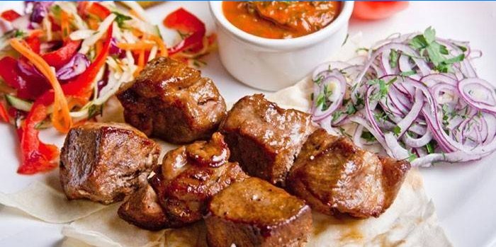 Carne de cerdo en rodajas con ensaladas y salsa