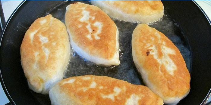 Las empanadas de masa de queso cottage se fríen en una sartén