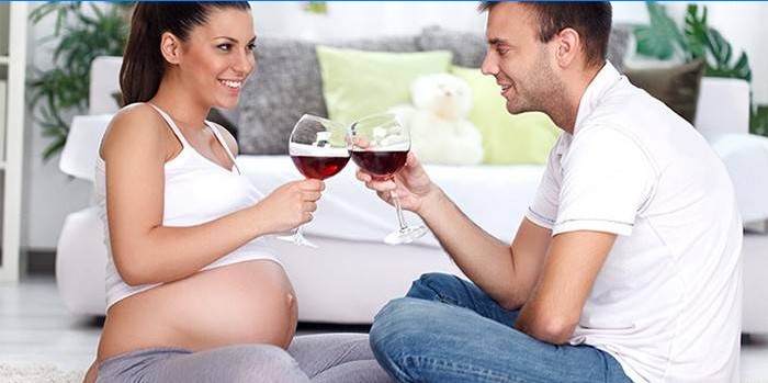 Mujer embarazada bebe vino en compañía de un hombre