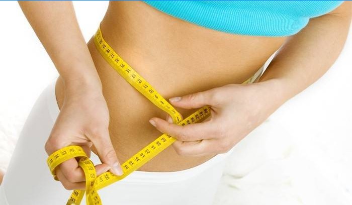 La mujer mide el volumen de la cintura después de perder peso.
