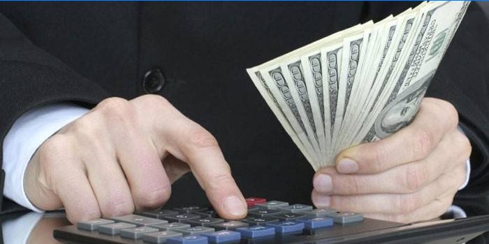 Un hombre cuenta con una calculadora y tiene billetes en la mano.