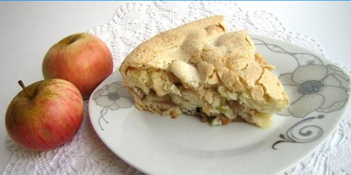 Una rebanada de pastel de manzana en un plato y manzanas