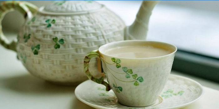 Té verde con leche en una taza y tetera