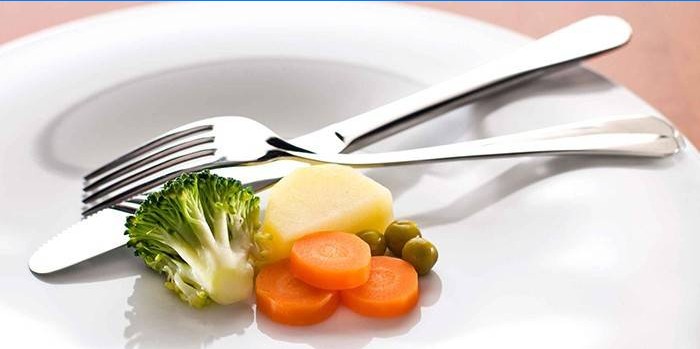 Pequeña porción de verduras en un plato y tenedor