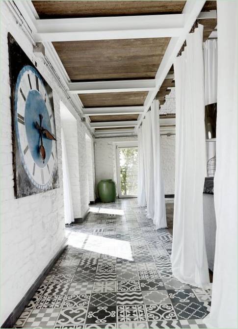 Las paredes de ladrillo blanco combinadas con azulejos grises y negros dan un toque fresco a la habitación