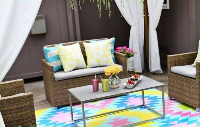 Diseño de porche con muebles de mimbre y alfombra de colores